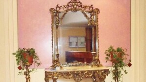 An ornate mirror with a gold frame, flanked by two potted plants. - Hotel York (Cinisello Balsamo)