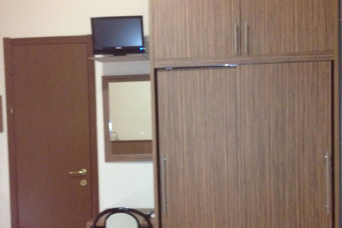 A room with a wardrobe, a desk, and a chair.