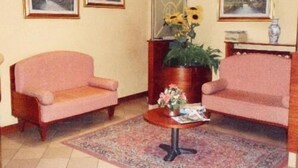 A living room with two armchairs, a coffee table, and three framed landscape paintings on the wall. - Hotel York (Cinisello Balsamo)