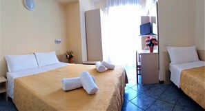 Une chambre d’hôtel avec deux lits, une télévision, un bureau et une fenêtre avec des rideaux.