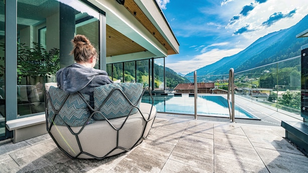 Ein moderner Sitzbereich im Freien mit Blick auf eine Berglandschaft und einen Pool.