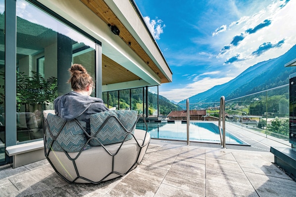 Una piscina al aire libre, sombrillas, sillones reclinables de piscina