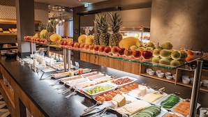 Ein Buffet mit verschiedenen Speisen, darunter Obst, Käse und Fleisch.