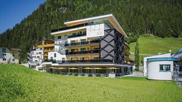 Ein modernes Hotel mit mehreren Balkonen, Sitzmöglichkeiten im Freien und einem Schild, das es als einen aktiven Naturresort kennzeichnet.