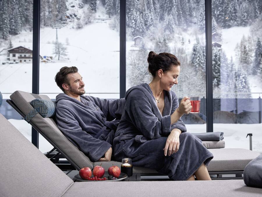 A couple in a cozy, modern room with a large window overlooking a snowy landscape.