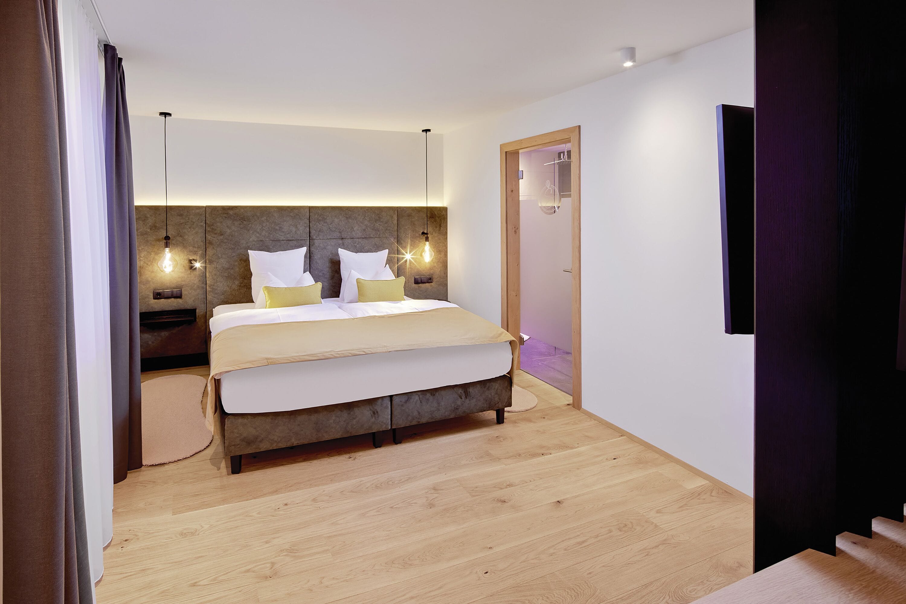 A modern bedroom with a large bed, bedside tables, and a built-in headboard.