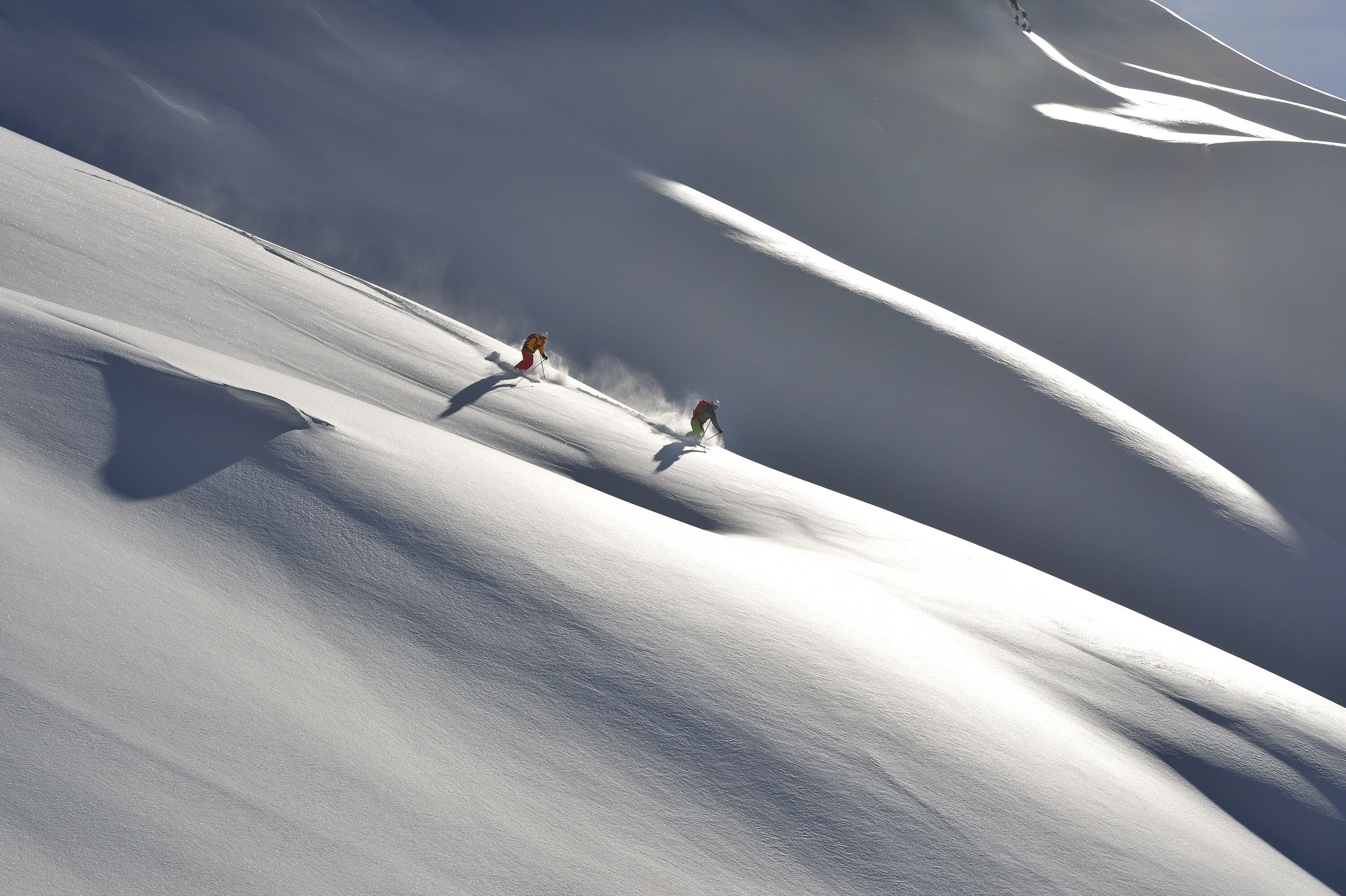 A snowy landscape with two skiers.