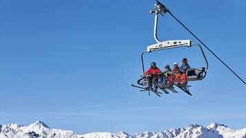 Un télésiège avec des skieurs portant des vestes rouges.