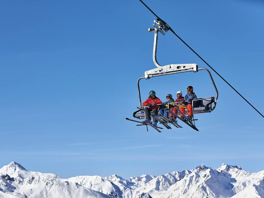 Un télésiège avec des skieurs portant des vestes rouges.