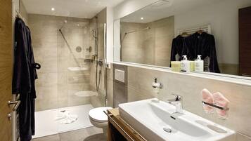 A modern bathroom with a large sink, a glass shower enclosure, and a toilet.