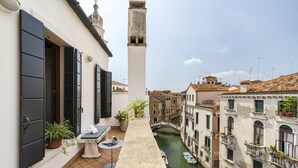 A narrow canal with boats, a stone balustrade, and buildings with balconies and windows.