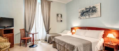 A hotel room with two beds, a TV, a wooden nightstand, a chair, and a table.