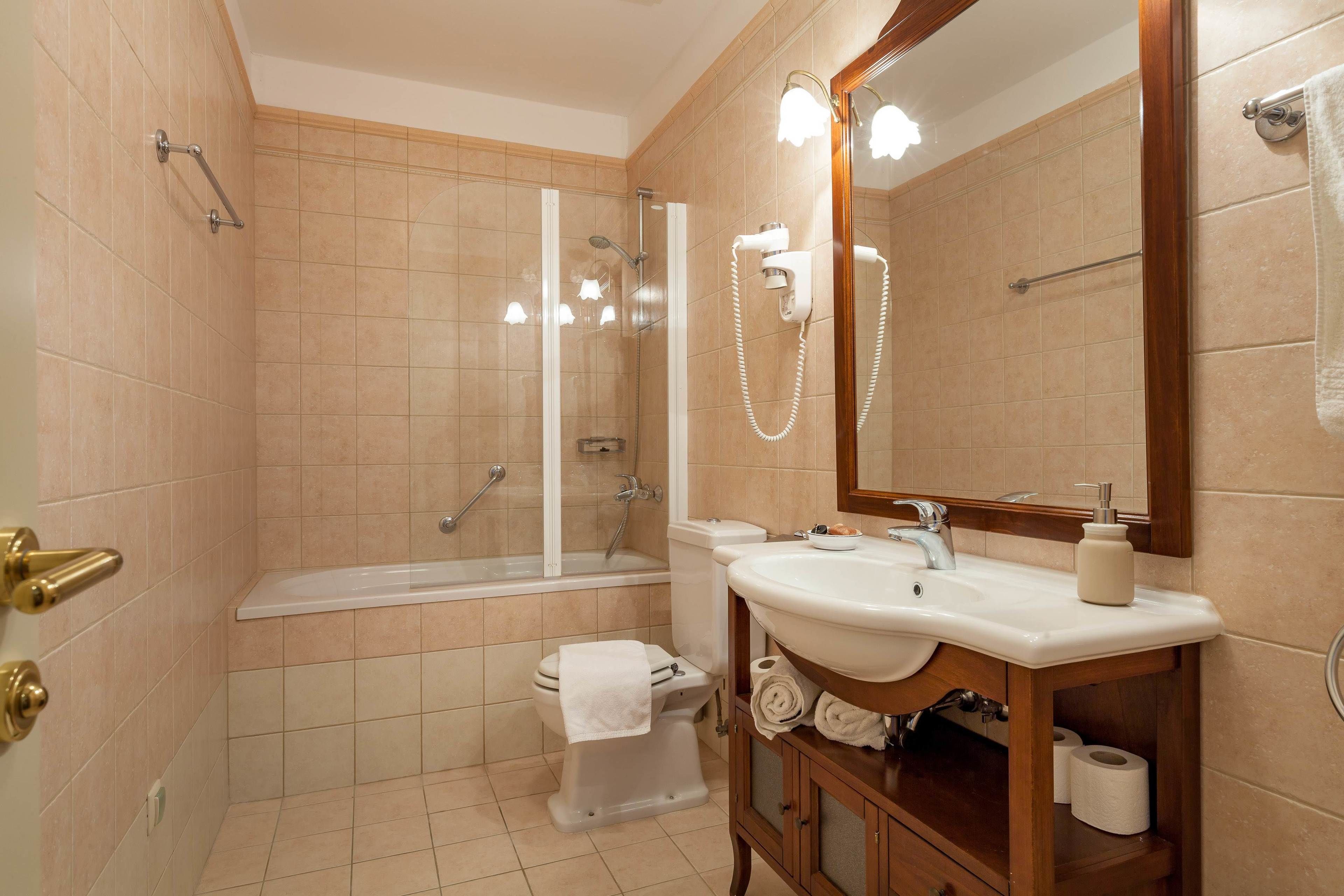 A modern bathroom with a bathtub, toilet, sink, and a large mirror.