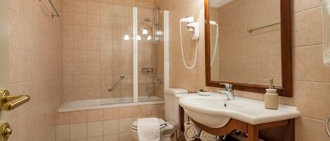 A modern bathroom with a bathtub, toilet, sink, and a large mirror.