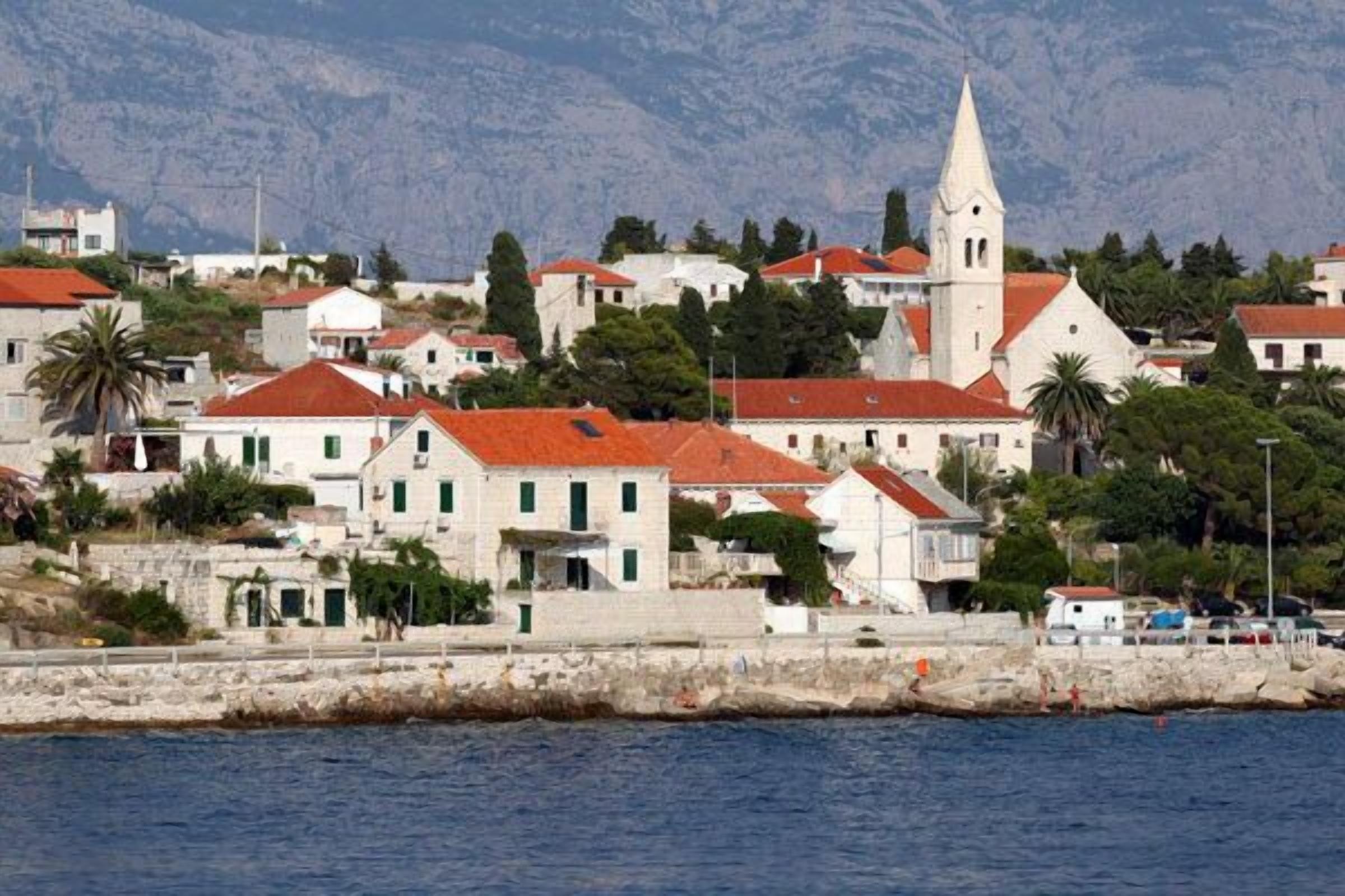 A coastal town with white buildings, red roofs, and a prominent church.