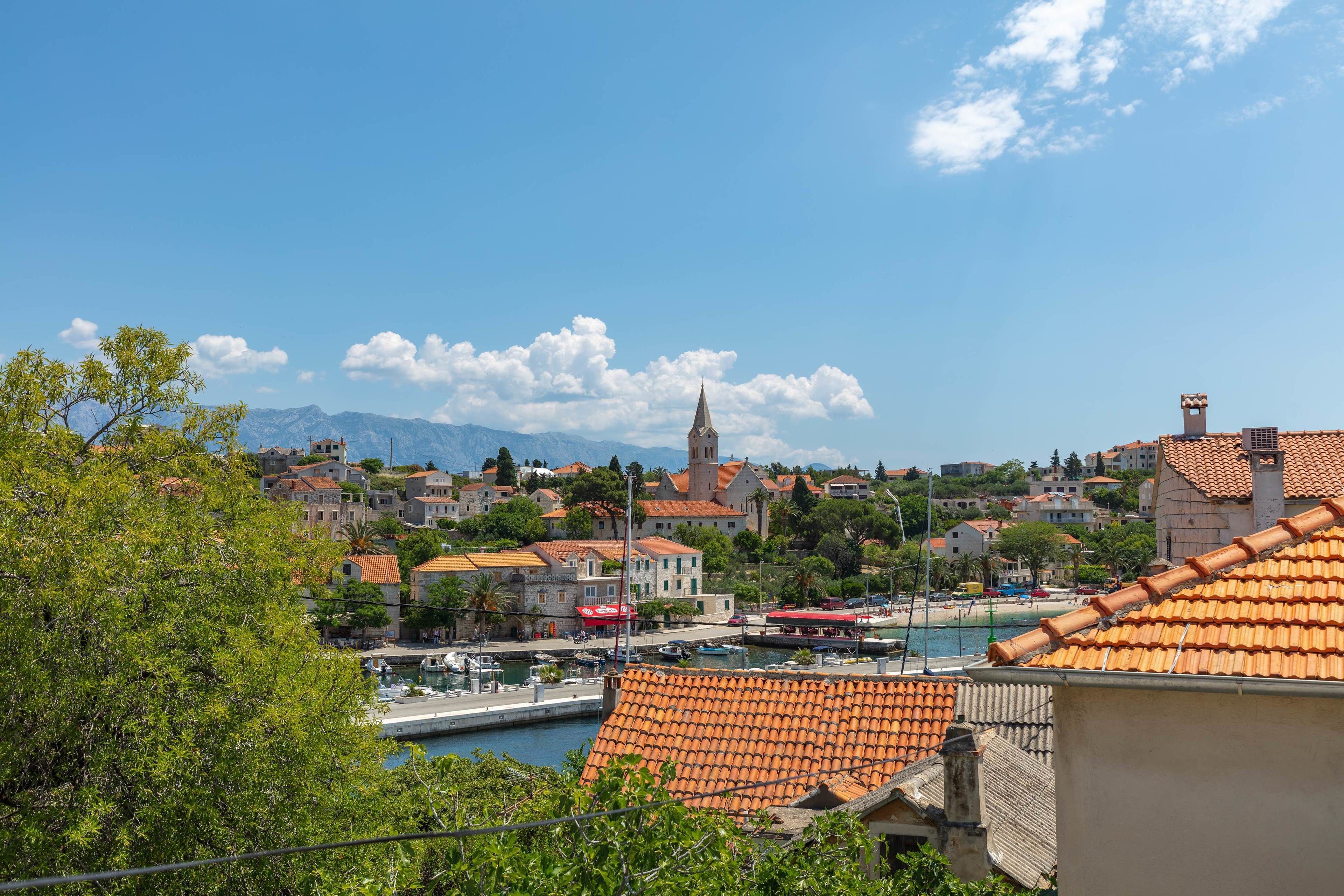 A coastal town with a prominent church, a marina, and terracotta-roofed buildings.