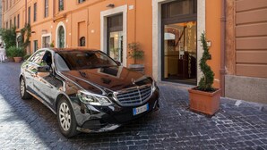 Un Mercedes-Benz negro estacionado frente a un hotel en una calle adoquinada.