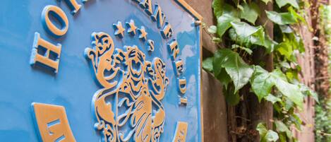 Un panneau bleu portant les inscriptions « HÔTEL MANHATTAN » et « HÔTEL-BOUTIQUE DE LUXE », indiquant un hôtel haut de gamme.