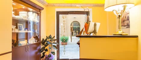 Un espace d’accueil d’hôtel comprenant une vitrine, une plante en pot et une lampe.