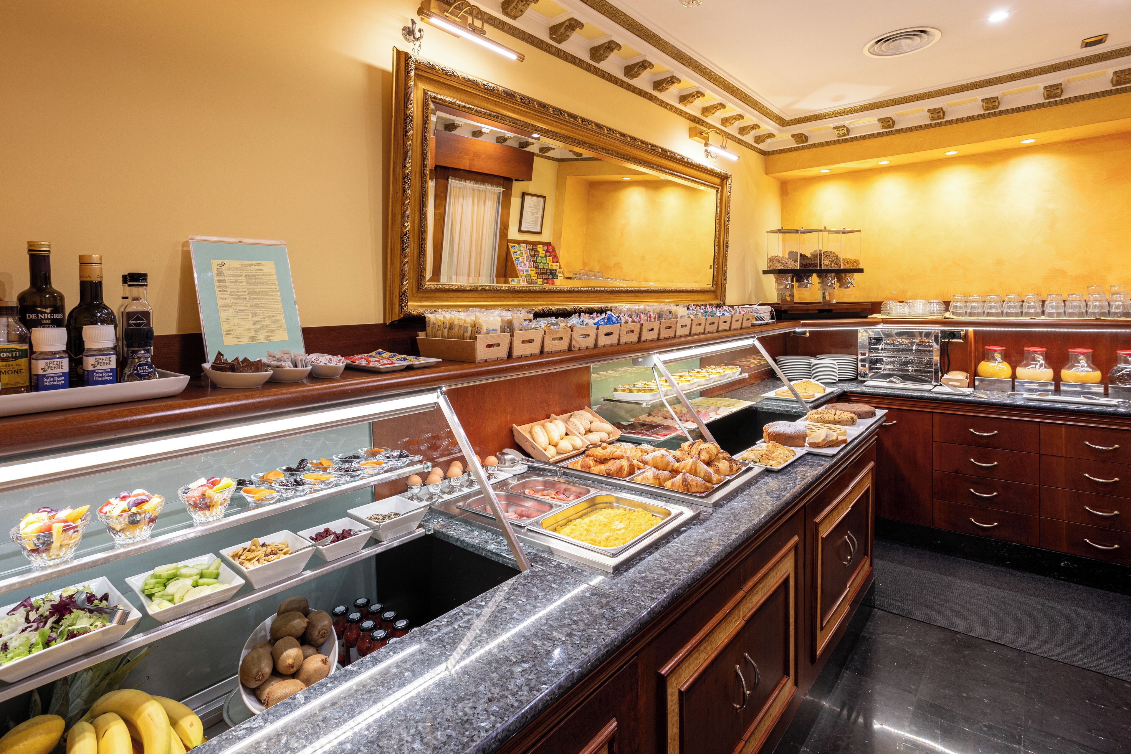 A buffet with various food items, a mirror, and a menu board.