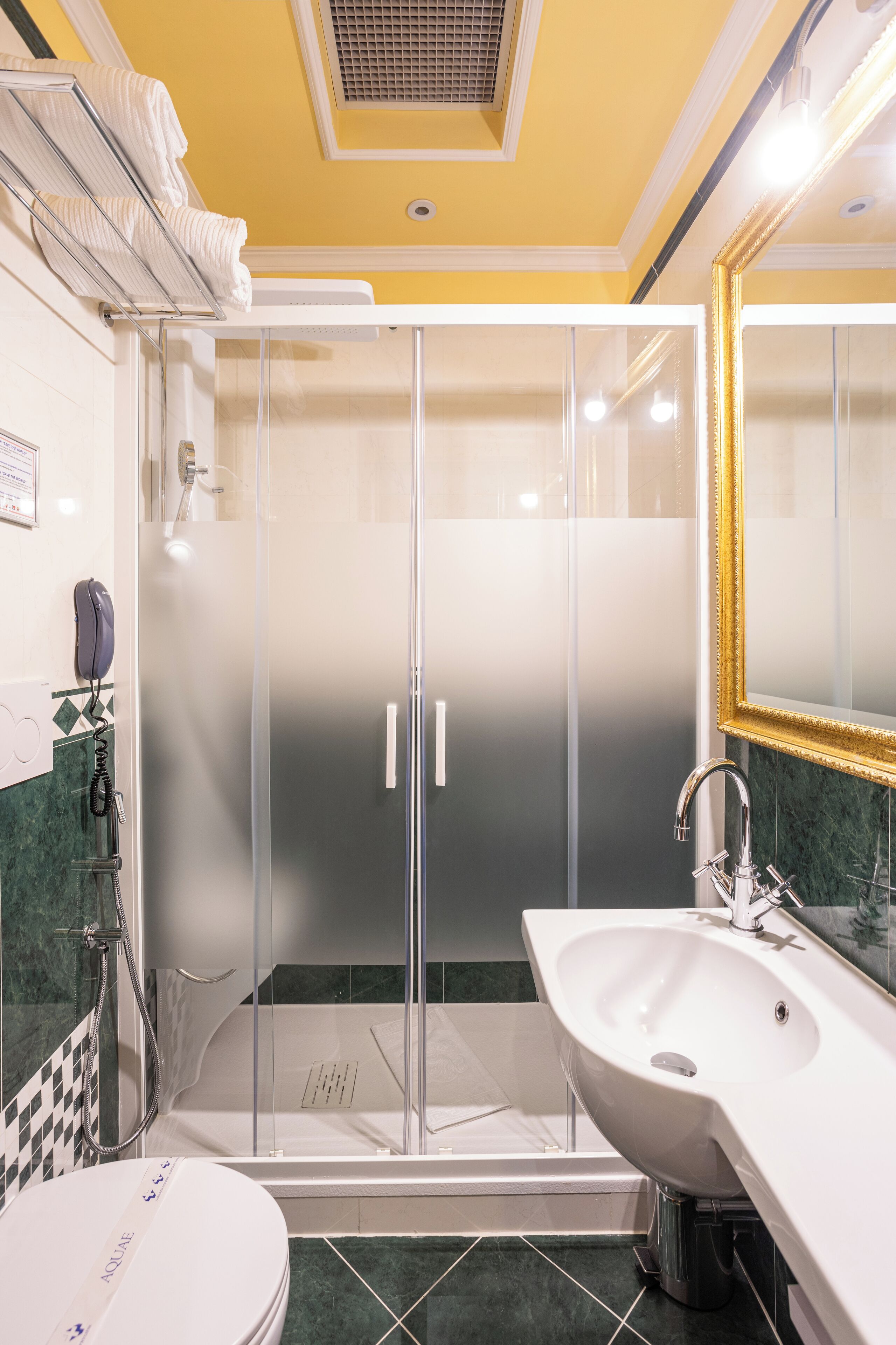 A modern bathroom with a glass-enclosed shower, a white sink, and a marble-tiled floor.