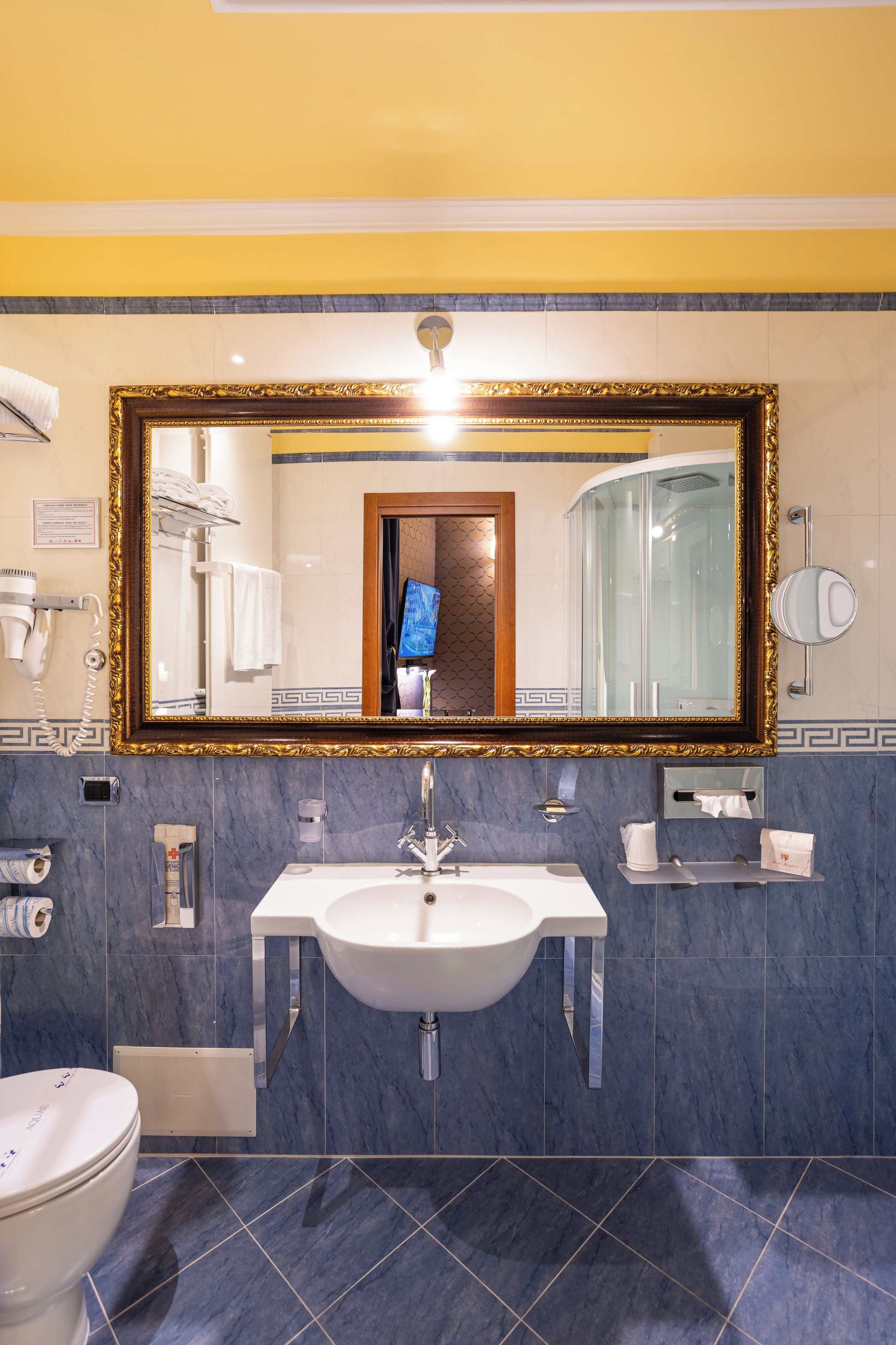 A bathroom with a large mirror, a sink, and a toilet.