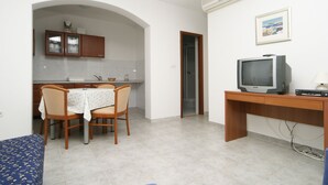 A compact living space with a dining area, a TV on a wooden stand, and a small kitchenette. - Apartments Pucisca (Pucisca)