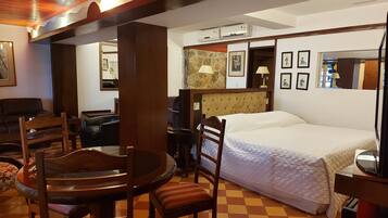 Una habitación de hotel con cama, una mesa de comedor con sillas, un sofá y un televisor.