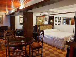 Una habitación de hotel con cama, una mesa de comedor con sillas, un sofá y un televisor.