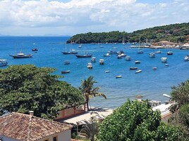 A coastal town with numerous boats docked in the harbor, surrounded by lush greenery and buildings with traditional architecture.