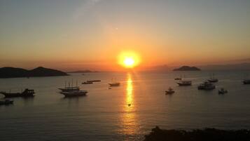 Um pôr do sol sobre um mar calmo com vários barcos.