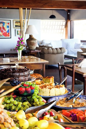 Un comedor con diversas opciones de comida, incluyendo un pastel de chocolate, frutas y una bandeja de pasteles.