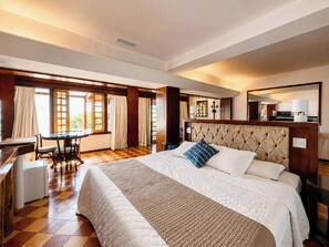 A hotel room with a large bed, a desk, and a dining table. - Sailing Hotel & Spa (Búzios)