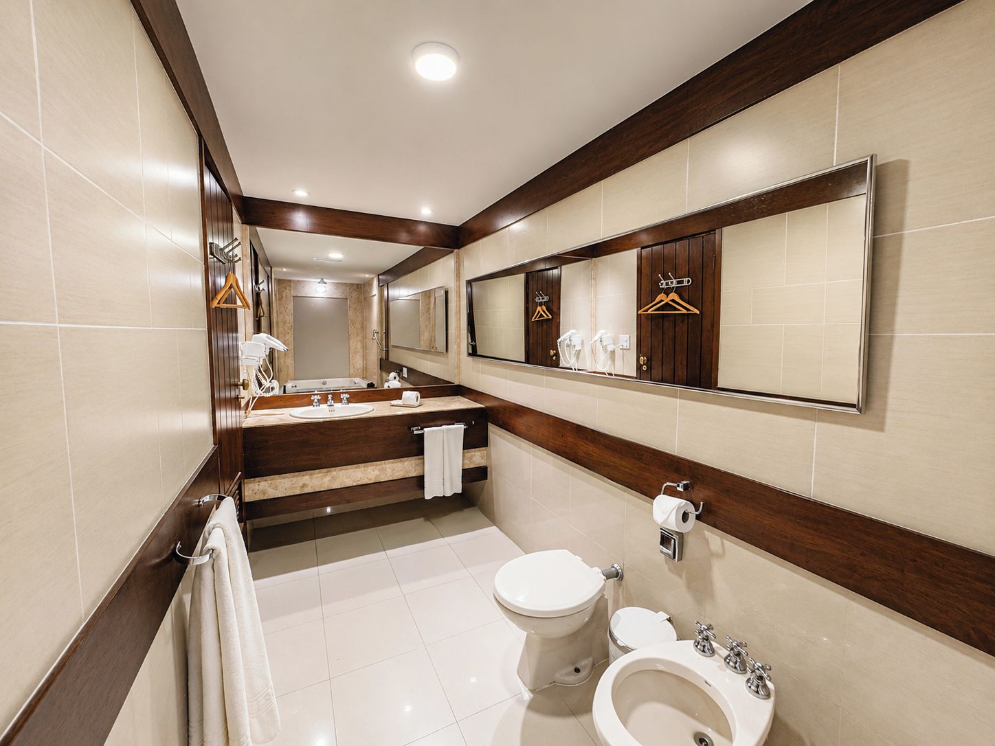 A modern bathroom with a vanity, toilet, bidet, and a large mirror.