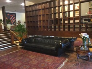 A lobby with a black leather sofa, a patterned rug, a wooden partition, and a staircase. - Sailing Hotel & Spa (Búzios)