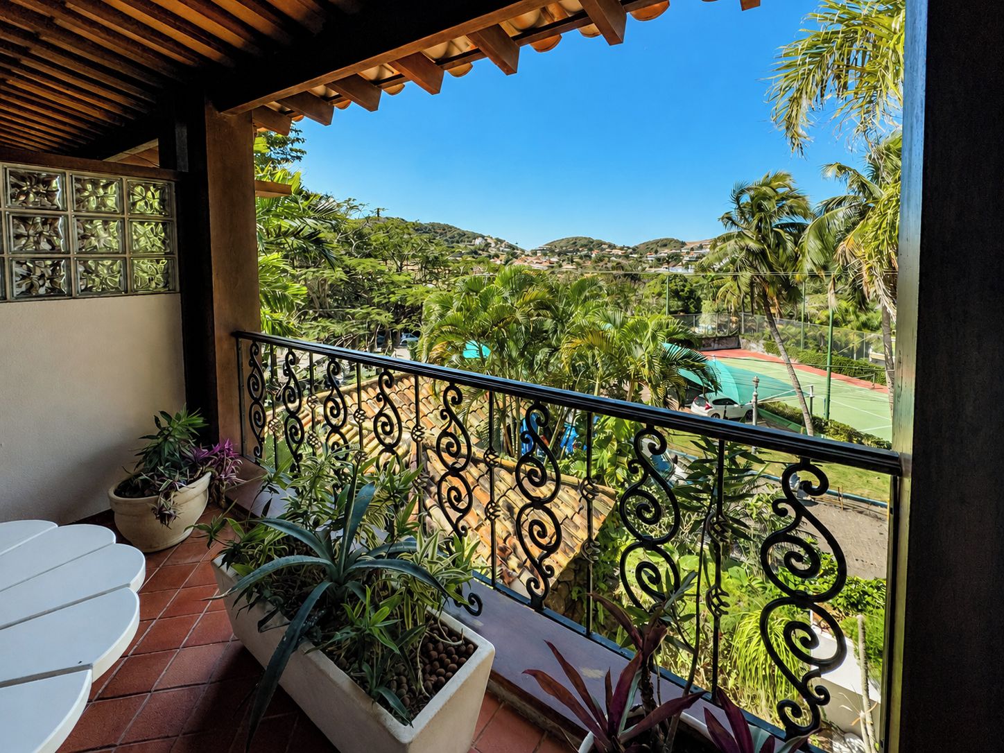 A balcony with a view of a tennis court and surrounding greenery.