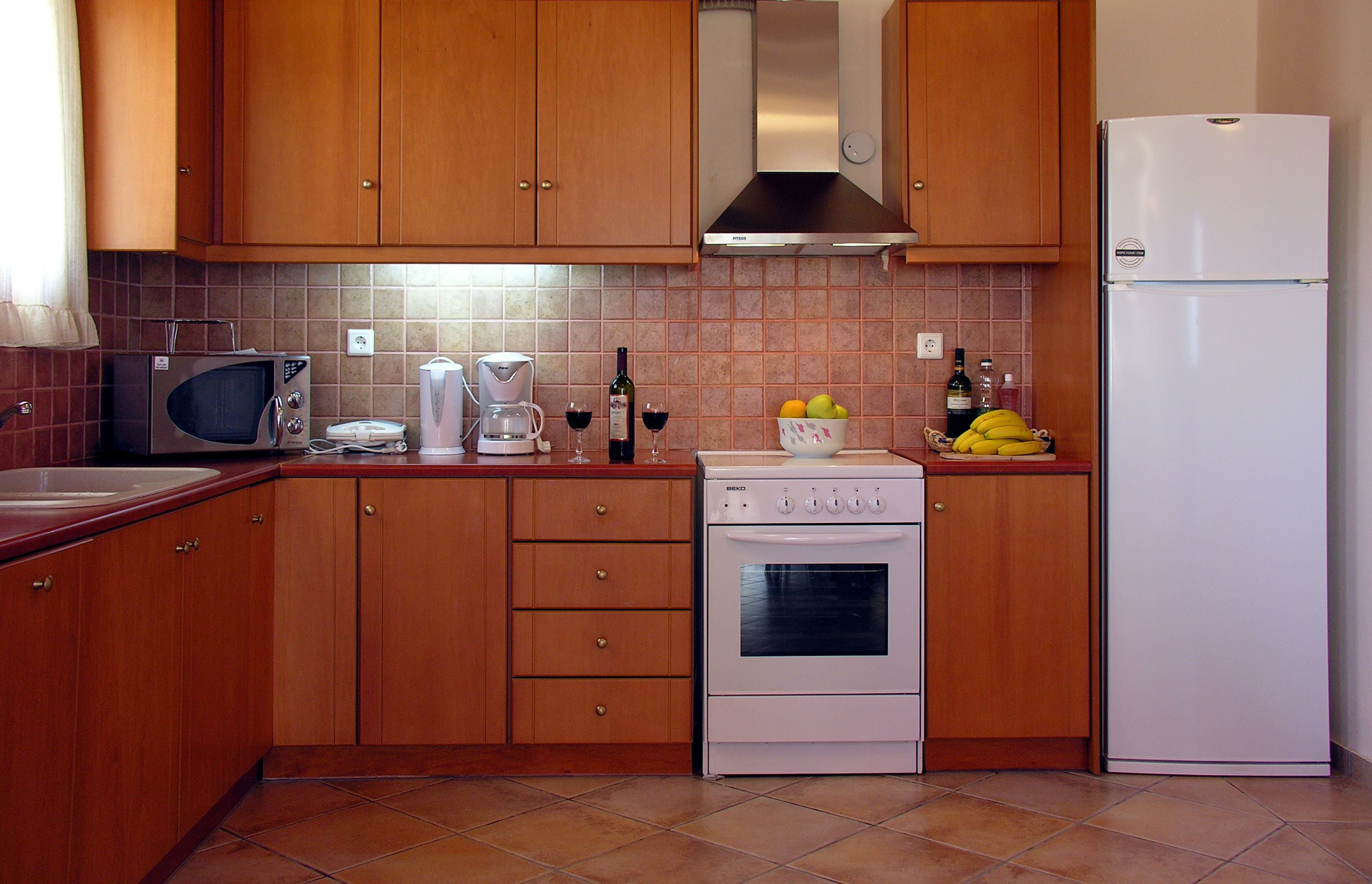 Une cuisine dotée de meubles en bois, d’un four à micro-ondes, d’une cuisinière, d’un réfrigérateur et d’un dosseret carrelé.