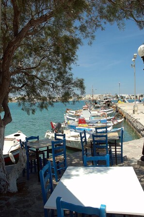 Un restaurante frente al mar con terraza, barcos amarrados cerca y vista despejada al agua.