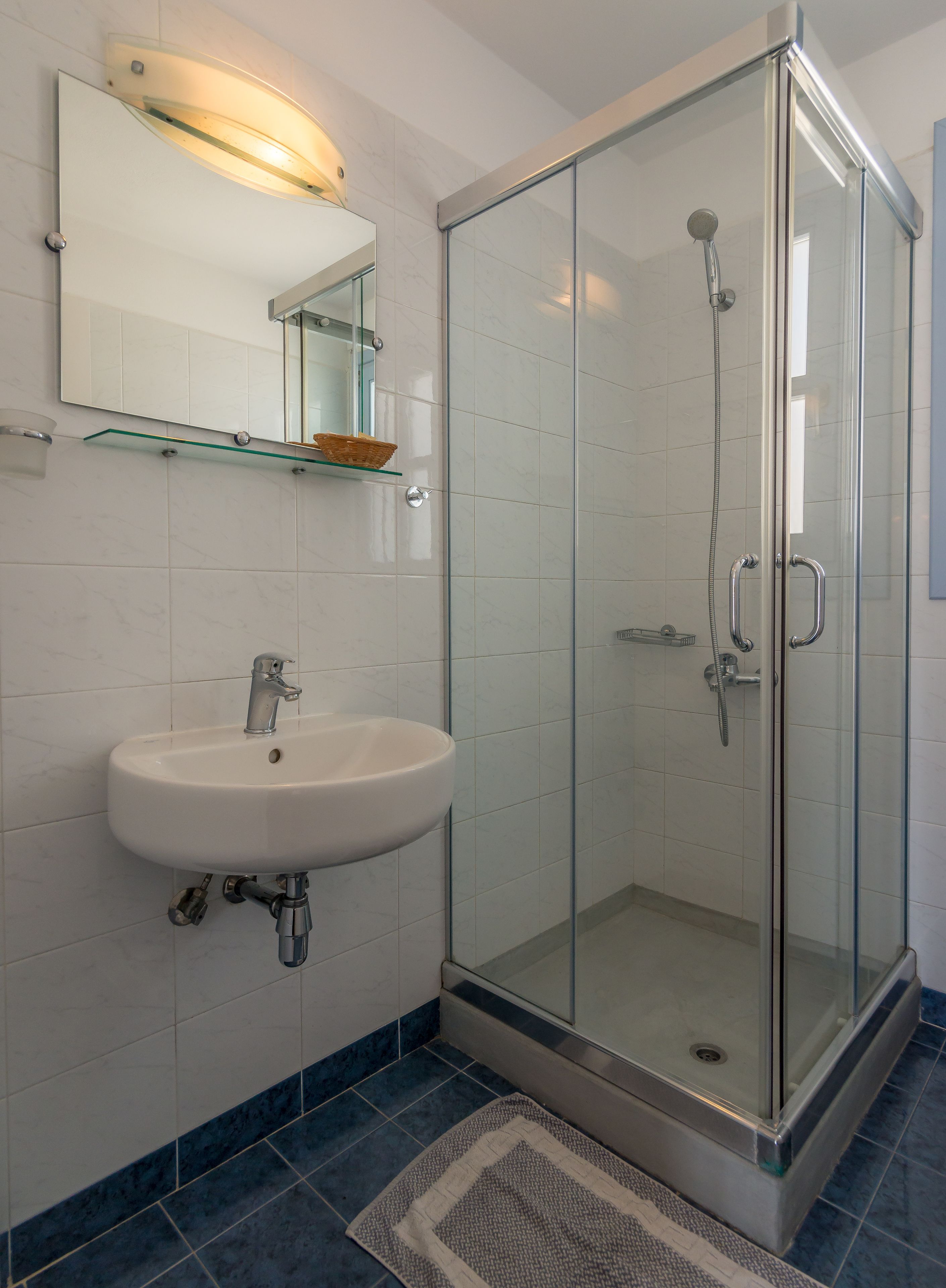 A bathroom with a glass-enclosed shower, a white sink, and a mirror above it.