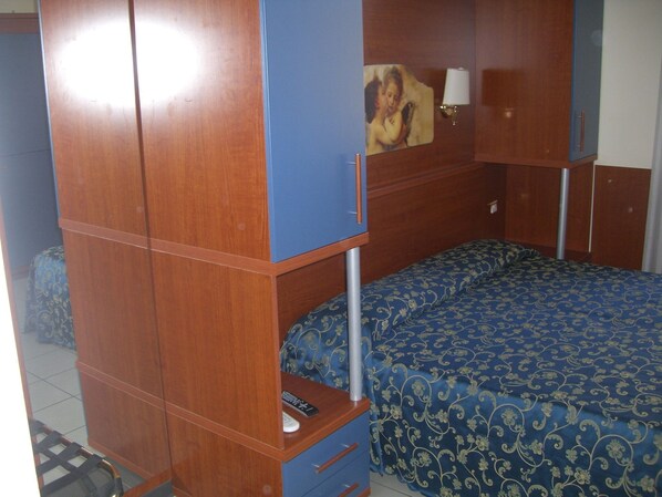 A room with a bunk bed, a desk with a lamp, and a painting on the wall.