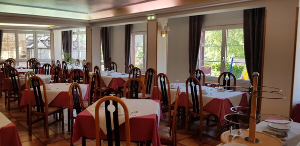 A restaurant with multiple tables, chairs, and a buffet stand.