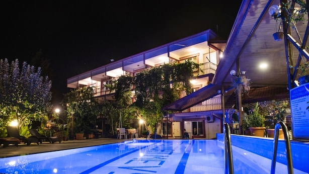 Una piscina con borde azul, rodeada de sillones de descanso y plantas en macetas.