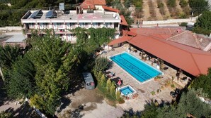 Vista aérea de un hotel con piscina, rodeado de árboles y un edificio con techo rojo.