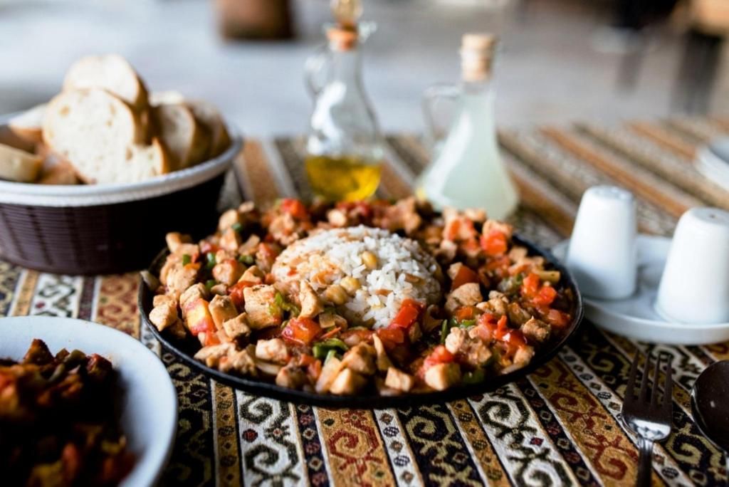 Una mesa de comedor con un plato de comida, un cuenco de pan y una botella de aceite.