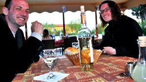 Una mesa de comedor con una botella de vino, una copa y un cesto de palitos de pan.