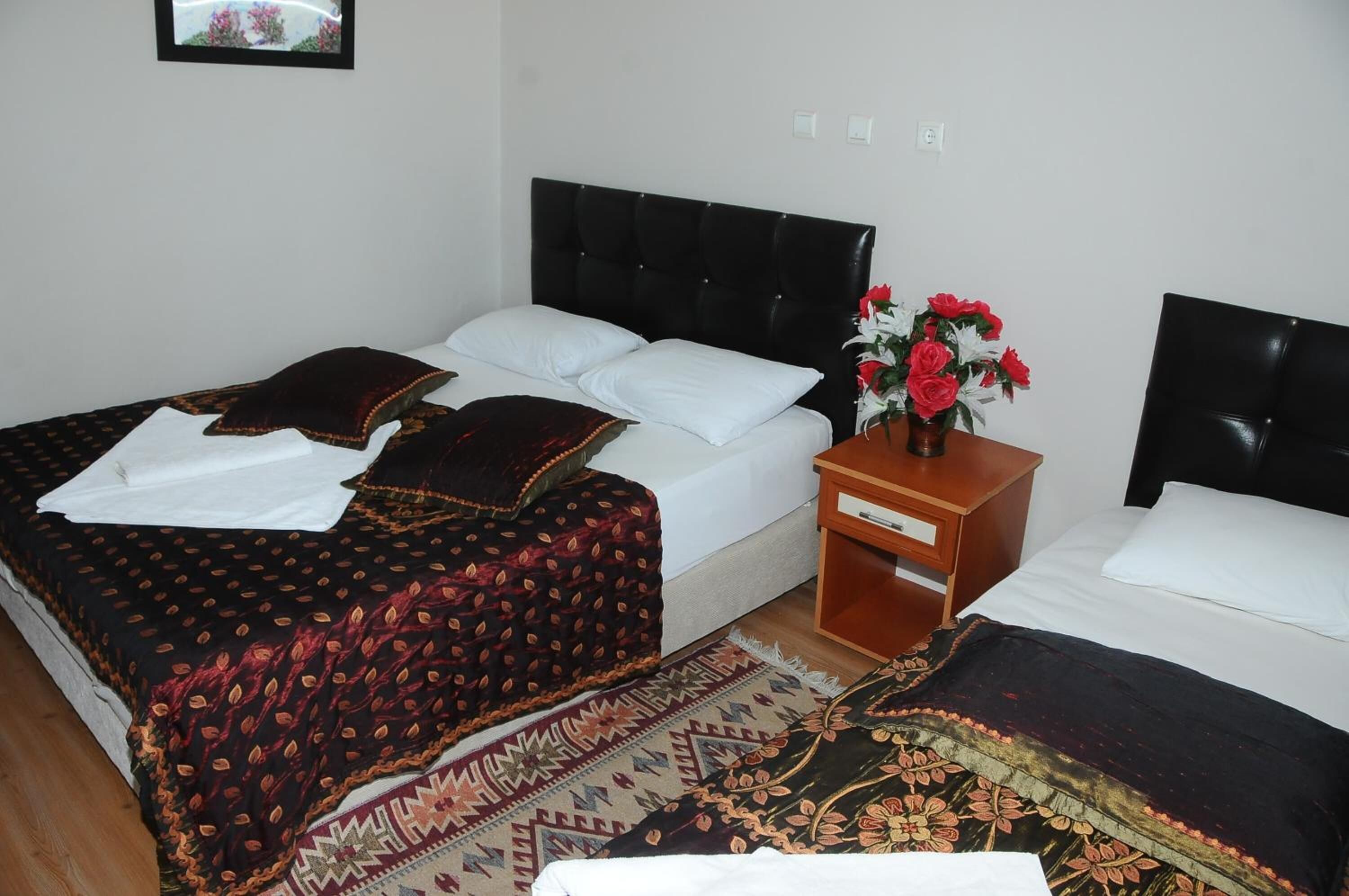 A hotel room with a bed, a nightstand with a vase of flowers, and a small table.