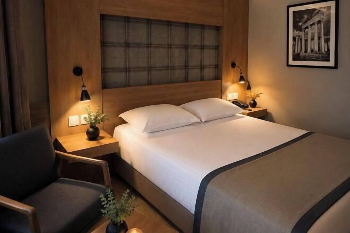 A hotel room with a bed, bedside tables, a chair, and a framed picture on the wall.