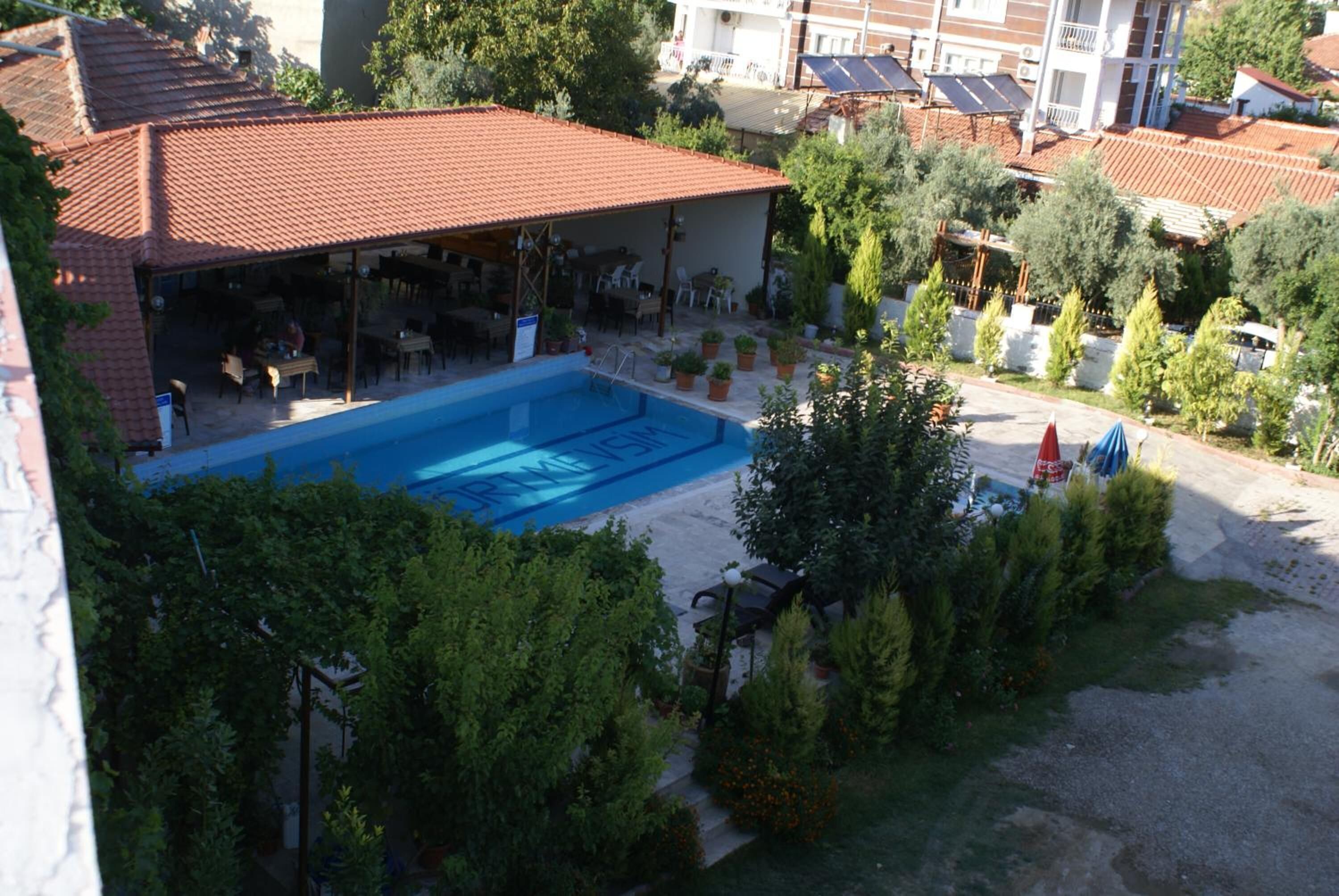 A swimming pool surrounded by potted plants and outdoor seating.