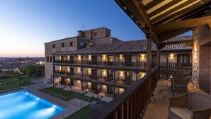 Un edificio de varios pisos con piscina, mobiliario exterior y vistas a la ciudad.