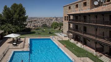 En swimmingpool med utsikt över stadsbilden, en täckt uteplats och en byggnad med ett tak täckt av tegelpannor.